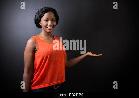 Ou de l'Afrique du Sud African American Woman enseignant ou étudiant hand out sur fond noir chalk board Banque D'Images