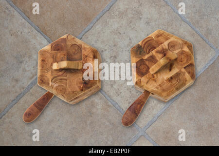 Deux pots de condiments en bois avec des cuillères et des couvercles sur un sol dallé Banque D'Images