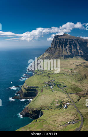 Falaises et un petit village, à Gásadalur, Pigalle, îles Féroé, Danemark Banque D'Images