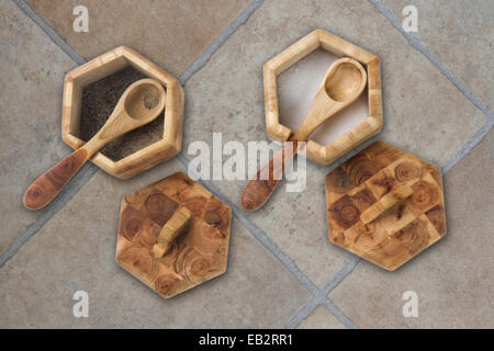 Deux pots de condiments en bois avec des cuillères et des couvercles sur un sol dallé Banque D'Images