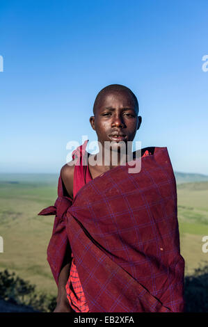 Un guerrier Massaï et herder bovins sur une montagne surplombant une plaine de savane. Banque D'Images