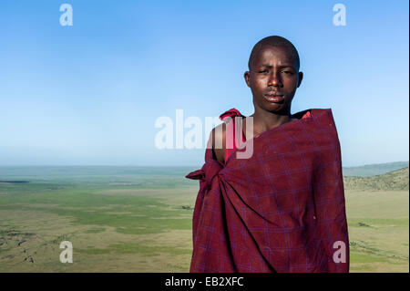 Un guerrier Massaï et herder bovins sur une montagne surplombant une plaine de savane. Banque D'Images