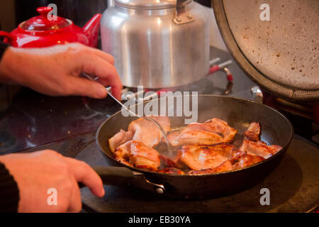 Bacon être frit dans une poêle sur une cuisinière. Banque D'Images