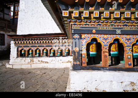 Roues de prière colorés et façades peintes le long du mur d'un ancien monastère Bouddhiste. Banque D'Images