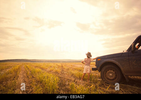 Mari boy leaning on car in rural field Banque D'Images