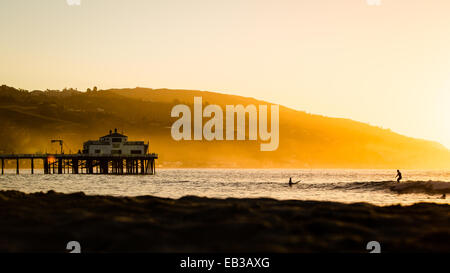 Silhouette de surfeurs et jetée au lever du soleil, Malibu, Californie, États-Unis Banque D'Images