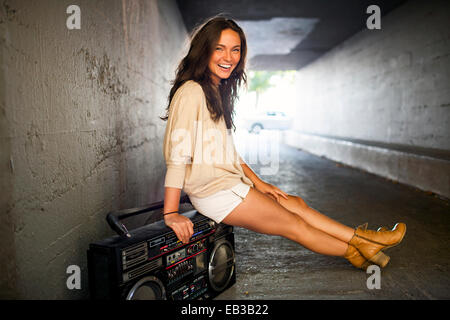 Caucasian woman sitting sur boom box in tunnel Banque D'Images