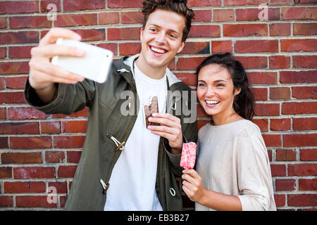 Couple en tenant près de selfies mur de brique rouge Banque D'Images