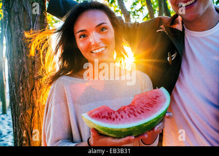 Caucasian couple eating watermelon at sunset Banque D'Images