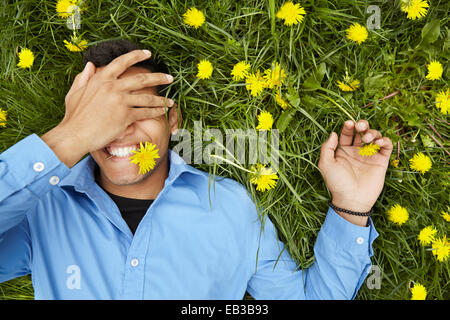 Smiling man laying in champ de fleurs Banque D'Images