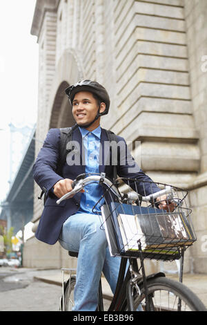 Smiling man riding bicycle on city street Banque D'Images