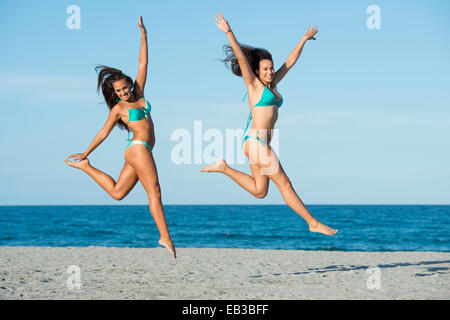 Les femmes sautant de joie sur la plage Banque D'Images