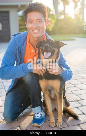 L'homme coréen hugging dog in driveway Banque D'Images