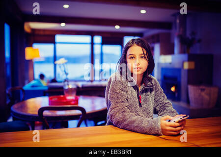 Mixed Race girl using cell phone at table Banque D'Images