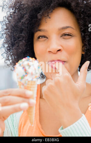 Smiling woman eating ice cream cone Banque D'Images