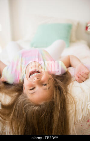Caucasian girl playing on bed Banque D'Images