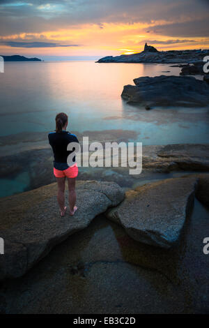 France, Corse, Femme regardant le coucher du soleil à beach Banque D'Images