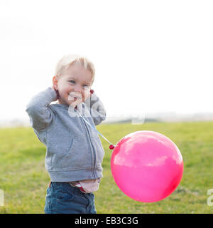 Boy holding a pink balloon Banque D'Images