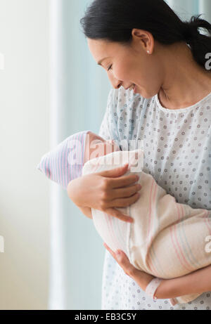 Asian mother holding newborn baby in hospital