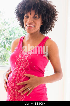 Pregnant African American mother holding sa Banque D'Images