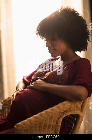 Pregnant African American mother holding sa Banque D'Images