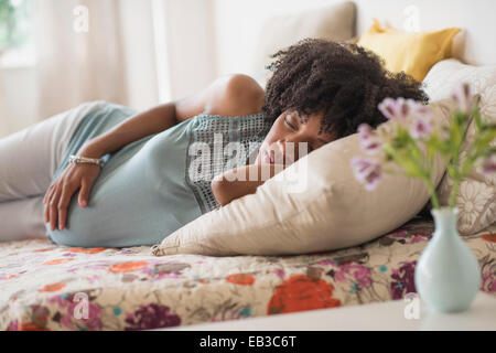 Pregnant African American mother holding her stomach in bed Banque D'Images