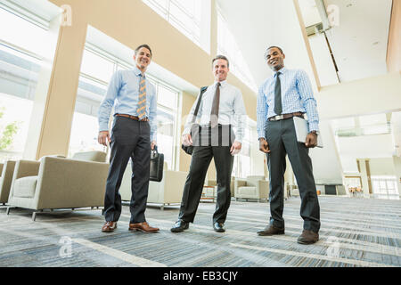 Low angle view of businessmen smiling in office lobby Banque D'Images