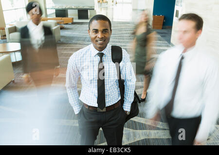 Businessman standing in office lobby toujours occupé Banque D'Images