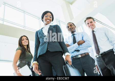 Low angle view of business people smiling in office lobby Banque D'Images