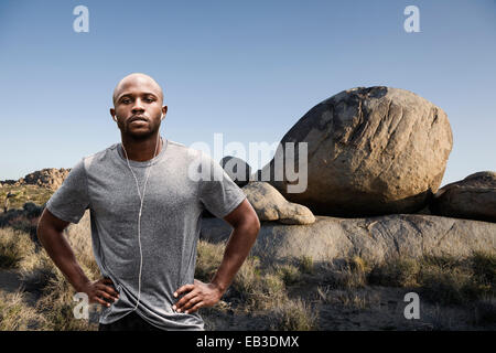 Black runner standing in rocky landscape à distance Banque D'Images