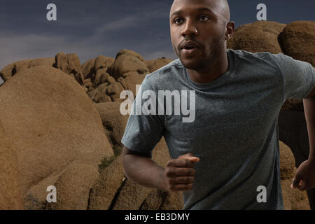 L'homme noir dans l'exécution à distance rocky landscape Banque D'Images