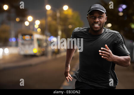 Black man running on city street at night Banque D'Images