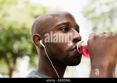 Black runner boire du jus en ville avec écouteurs Banque D'Images