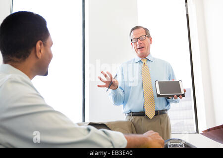 Businessman showing digital tablet to colleagues in meeting Banque D'Images