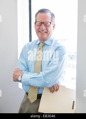Caucasian businessman holding folder in office Banque D'Images