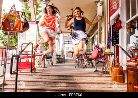 Caucasian teenage girls sauter de joie dans la ville Banque D'Images