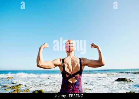 Older Caucasian woman flexing muscles on beach Banque D'Images