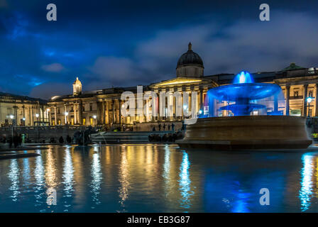 Fontaine illuminée à Trafalgar Square la nuit avec National Gallery en arrière-plan. Banque D'Images