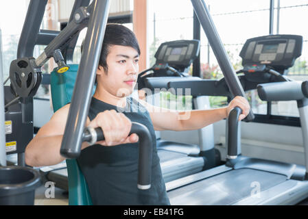 L'homme fit l'exercice à la salle de sport sur une machine Banque D'Images