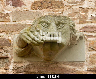 Pierre étrange gargouille, sur mur à la cathédrale de Brecon au Pays de Galles, avec main tenant le pour montrer la bouche grande ouverte Banque D'Images