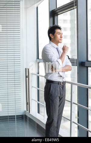 Young businessman looking through window Banque D'Images