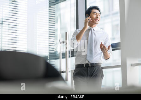 Young businessman talking on cell phone in office Banque D'Images