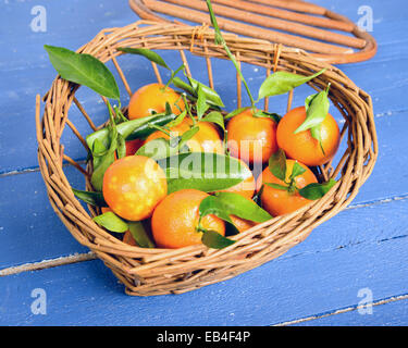 Petit panier plein de mandarines sur tableau bleu Banque D'Images