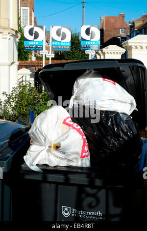 Les ordures ménagères débordante wheelie bins collection attendent depuis l'avant jardin d'une maison urbaine Banque D'Images