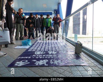 Chine Chinois du continent mère unique écrit sur le sol. calligraphie de sable Elle prétend que sa fille a besoin d'argent pour les tr Banque D'Images