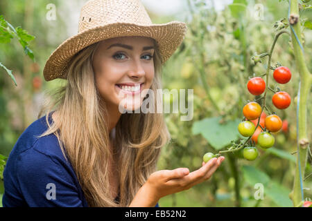 Jolie blonde à la plante de tomate à Banque D'Images