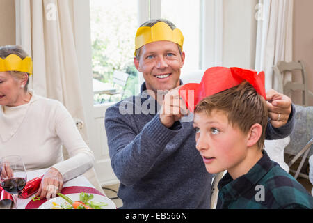 Smiling father putting party hat sur fils head Banque D'Images
