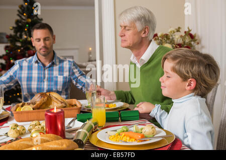 Famille élargie disant grace avant Noël diner Banque D'Images