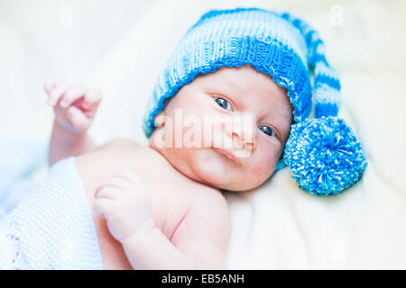 Nouveau-né pacifique bébé couché sur un lit en souriant sur feuilles blanches Banque D'Images