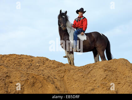 Dans l'homme vêtements cowboy rides bareback sur un cheval repéré sur une colline de sable Banque D'Images